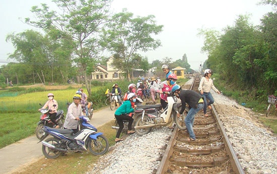 Nhiều người nôn nóng hơn, khiêng xe máy qua đường tàu. Ảnh: THANH NGHỊ