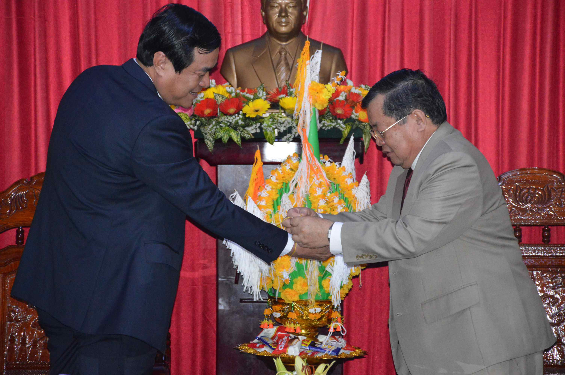 Consul General Phommaseng Khamsene (right) fastens the thread on Mr Cuong’s wrist as a traditional ritual of Lao New Year