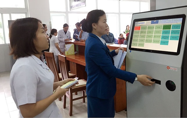Thay đổi quy trình khám bệnh giúp người bệnh giảm thời gian chờ đợi. Trong ảnh: Nhân viên hướng dẫn lấy số đăng ký khám tự động cho bệnh nhân.