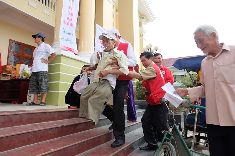 Cán bộ Hội Chữ thập đỏ giúp đỡ người dân đến khám chữa bệnh. Ảnh: M.L