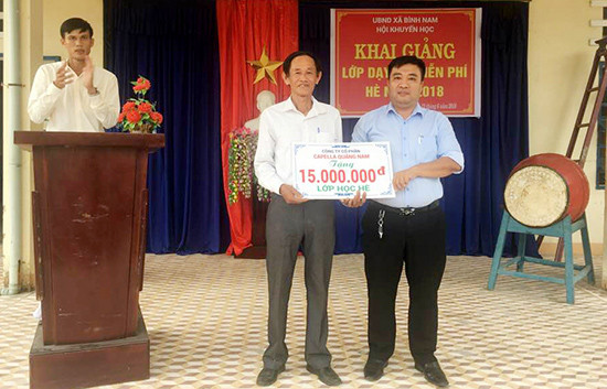 Ông Sự (bên trái) vui mừng nhận tiền hỗ trợ của Công ty CP Capella Quảng Nam trong buổi khai giảng lớp học hè. Ảnh: NVCC
