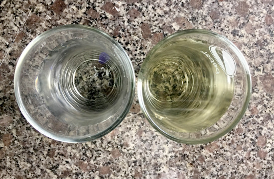 So sánh giữa ly nước lọc (bên trái) với nước từ giếng bơm lên (bên phải). Ảnh: QUÂN VINH