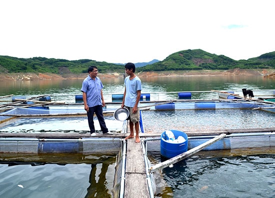 Anh Trần Thanh Tuân trao đổi với ông Khương Đình Thương về kỹ thuật nuôi cá trong lồng bè. Ảnh: V.Q