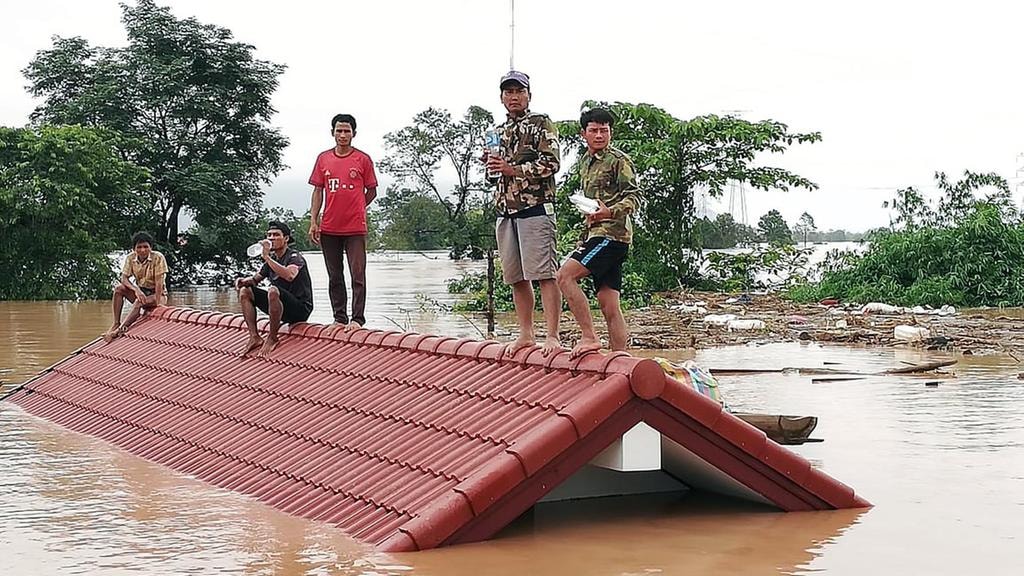 Nhiều người mắc kẹt trên các nóc nhà sau vụ vỡ đập nghiêm trọng tại Lào vào tối 21.7 vừa qua. Ảnh: EPA