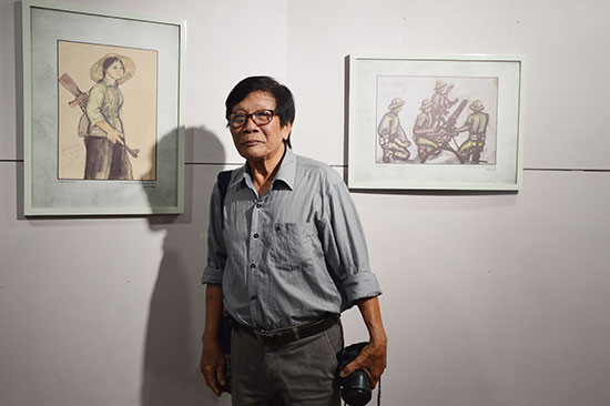 Nhà điêu khắc, họa sĩ Phạm Hồng bên những bức ký họa của mình tại triển lãm.