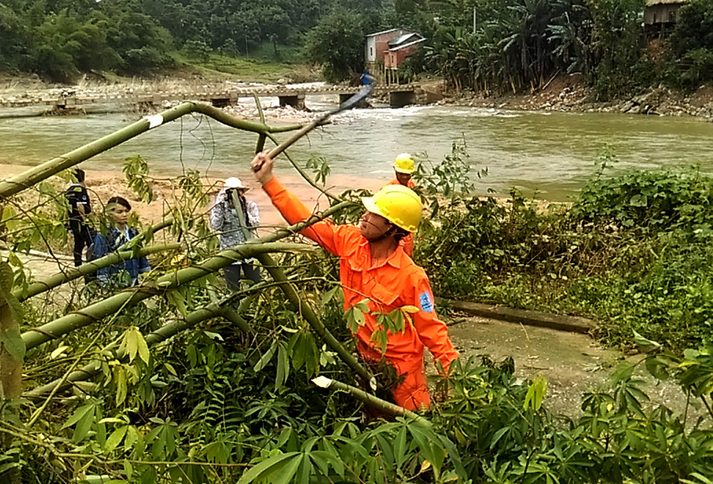 Nhân viên điện lực Nam Trà My phát dọn những cây rưng ngã đổ sát tuyến điện. Ảnh: THẮNG QUÂN