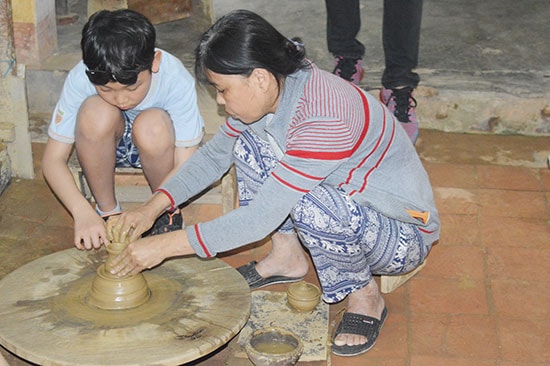 Thợ gốm ở làng nghề hướng dẫn cách làm gốm. Ảnh: Q.TUẤN