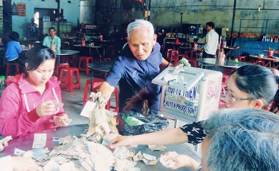 Ông Trần Văn Sửu kiểm tra thùng từ thiện đặt tại một quán ăn ở Phước Sơn. Ảnh: KHÂM ĐỨC