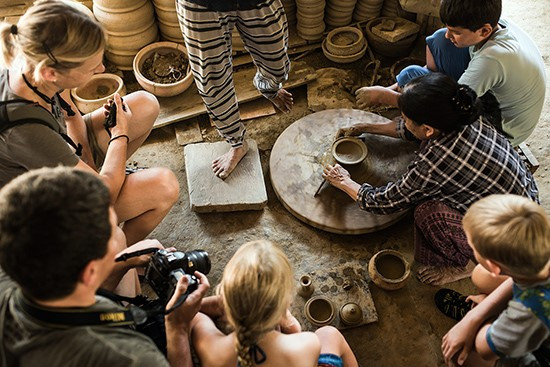 Foreign tourists are impressed by the techinique of making pottery in Thanh Ha village.