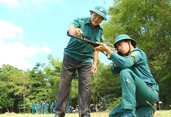 Chính trị viên Lê Xuân Long (bên trái) hướng dẫn thao tác bắn súng cho chiến sĩ dân quân. Ảnh: XUÂN SƠN