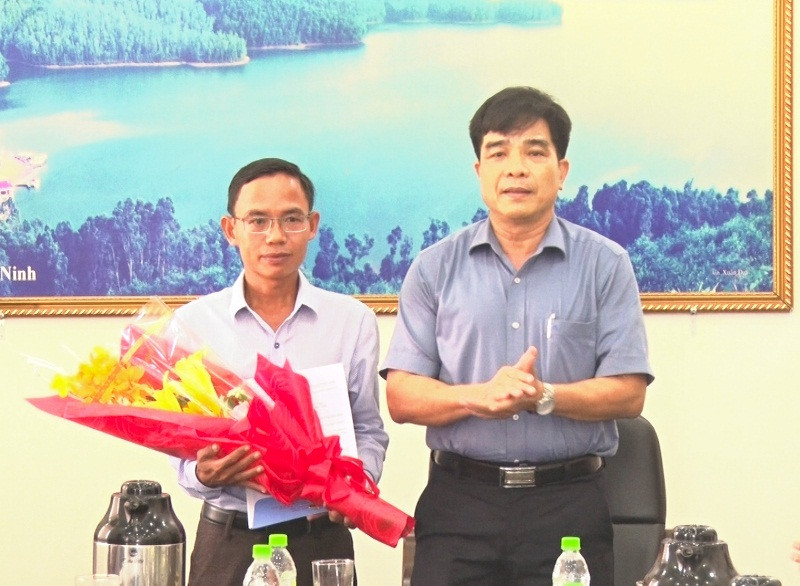 Trưởng Ban Tổ chức Tỉnh ủy Lê Văn Dũng (phải) trao quyết định chuẩn y và tặng hoa chúc ông Huỳnh Xuân Chính. Ảnh: V.C