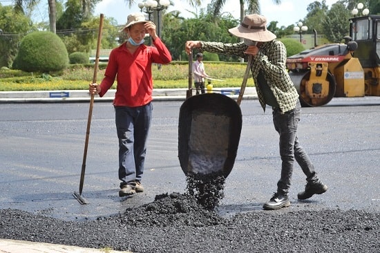 Công nhân vận chuyển nguyên liệu bê tông nhựa từ nơi thừa sang nơi thiếu. Ảnh: CT