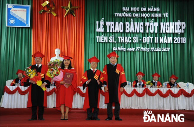PGS, TS Nguyễn Ngọc Vũ (thứ hai, phải sang) trao bằng cho tân tiến sĩ đợt 2 năm 2018 tại Trường Đại học Kinh tế.