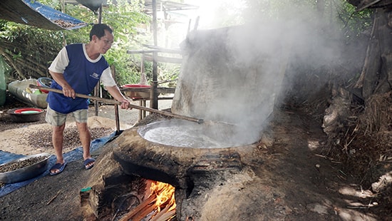 Ông Nguyễn Hữu Tứ luộc hến trong nồi gang to đặt giữa bếp lò làm bằng đất sét. 