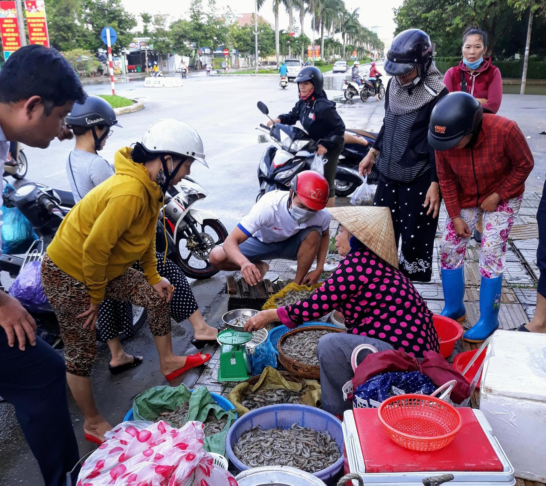 Chủ một hồ nuôi tôm bày bán tôm thẻ thu hoạch chạy lũ tại giao lộ Hùng Vương - Nguyễn Chí Thanh. Ảnh: B.A