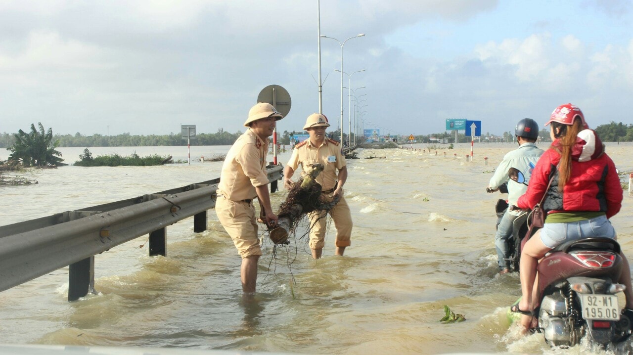 Những điểm nước hạ xuống ngưỡng an toàn, CSGT vừa túc trực, vừa khiêng dọn những gốc cây to chắn ngang cho xe qua lại. Ảnh: T.H