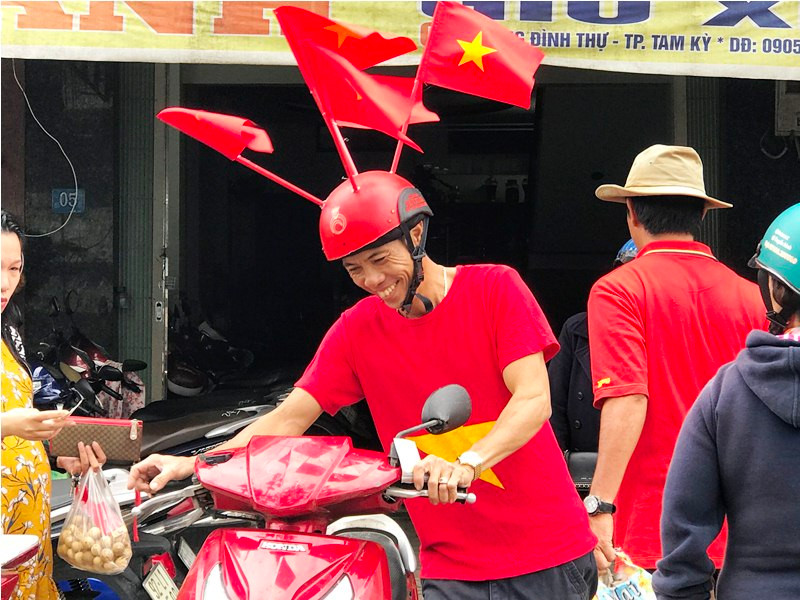 Anh Trương Văn Anh với chiếc mũ bảo hiểm độc đáo, vui vẻ giắc xe máy cho khách. Ảnh: VINH ANH