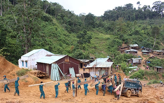 Dân quân A Nông tham gia giúp nhân dân thôn Arui (xã Dang) di dời nhà cửa về nơi ở mới trước mùa mưa bão. Ảnh: ĐÌNH HIỆP