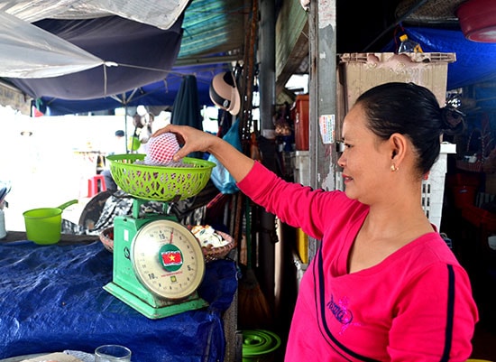 Chị Võ Thị Mộng Quyên cân táo Trung Quốc để bán cho khách hàng. Ảnh: QUANG VIỆT