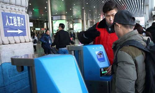 Hành khách sử dụng máy quét thẻ lên tàu ở một nhà ga đường sắt tại Bắc Kinh. Ảnh: VCG