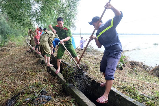 Đoàn thanh niên Công an tỉnh giúp dân dọn dẹp vệ sinh, khai thông kênh mương sau lũ. Ảnh: M.L