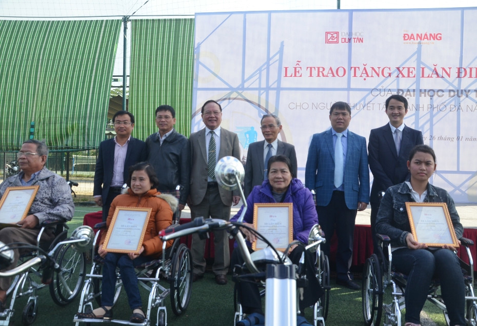 Lãnh đạo Trường ĐH Duy Tân trao xe lăn điện cho người khuyết tật. Ảnh: N.T.B