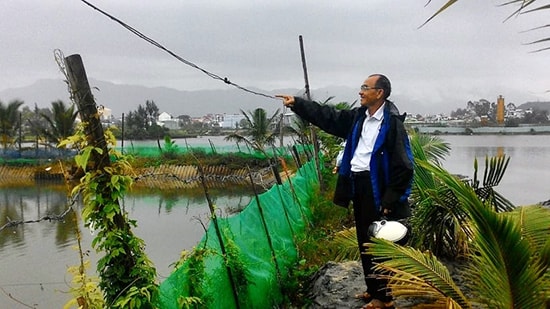 Ông Hoàng Dự giới thiệu mô hình nuôi tôm, kết hợp trồng dừa của mình. Ảnh: VĂN VIỆT