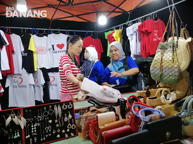 Để kích thích chi tiêu, thành phố nên đầu tư thêm các sản phẩm du lịch mới độc đáo.  Trong ảnh: Du khách mua đồ lưu niệm tại chợ đêm Sơn Trà.
