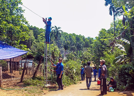 Lực lượng thanh niên tình nguyện lắp đặt công trình “ Thắp sáng đường quê” tại xã Trà Đông, Bắc Trà My, sau lễ phát động. Ảnh: T.ĐẠT