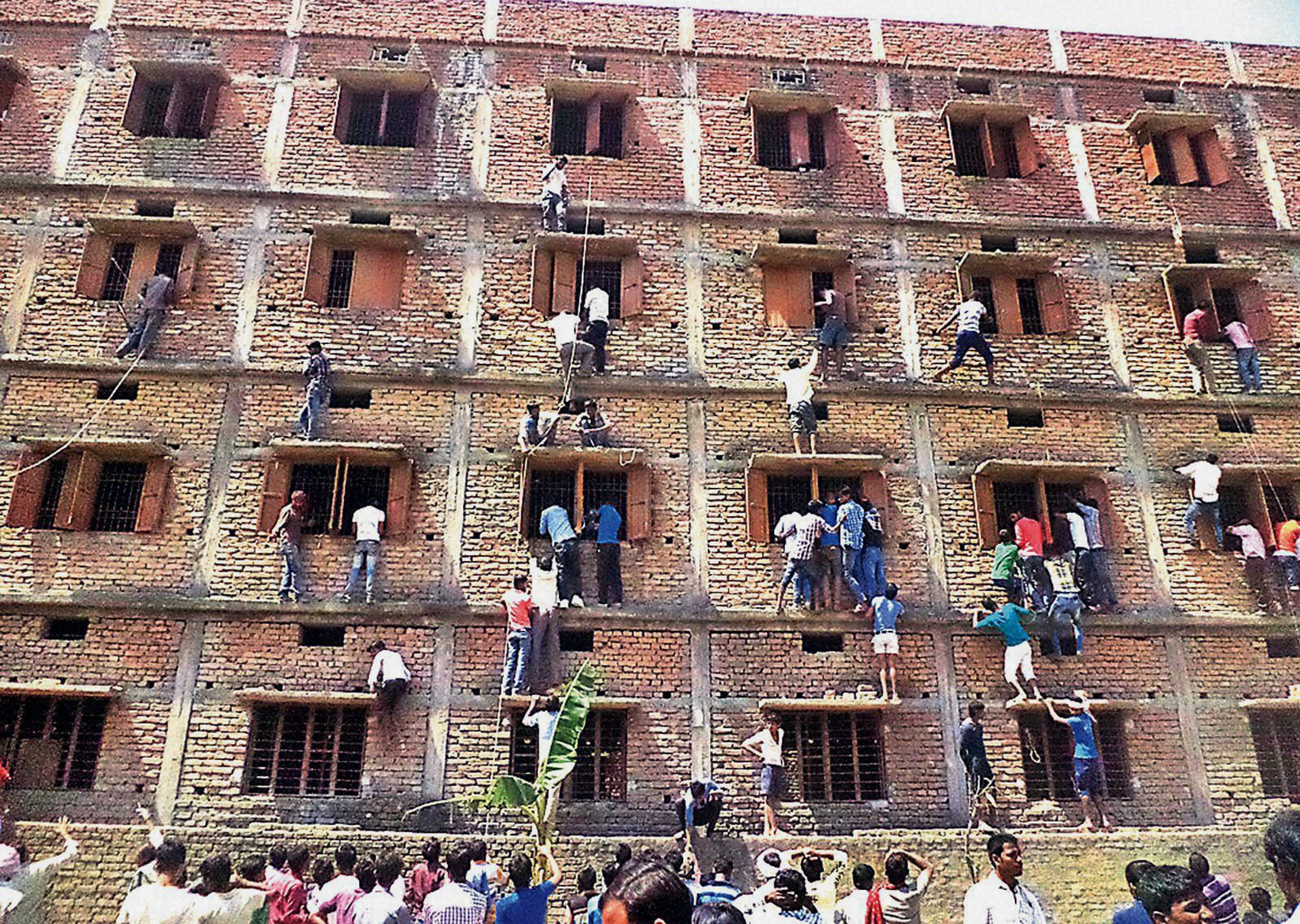 Nhiều phụ huynh đeo bám trên của sổ trường học cao tầng là hình ảnh thường thấy tại các kỳ tuyển sinh đại học tại Ấn Độ. Ảnh: AP