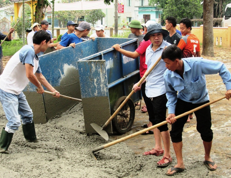 Các bạn đoàn viên tích cực tham gia đổ bê tông sân nhà văn hóa thôn Phú Bông (Duy Trinh, Duy Xuyên). Ảnh: HOÀI NHI