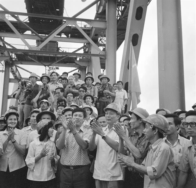11 giờ ngày 18-10-1983, Bộ trưởng Bộ Giao thông vận tải Đồng Sĩ Nguyên (giữa, áo trắng, đội mũ) cùng các chuyên gia Liên Xô và người lao động Việt Nam thực hiện nghi thức vặn chiếc bu-loong cuối cùng trên công trường xây dựng cầu Thăng Long, nối liền 2 bờ Nam Bắc của công trình mang biểu tượng của tình hữu nghị Việt-Xô này. Ảnh: Vũ Hanh/TTXVN.
