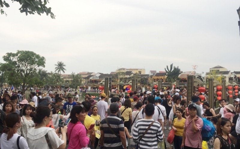 Visitors on the banks of the Hoai river which flows through the ancient quarter of Hoi An city