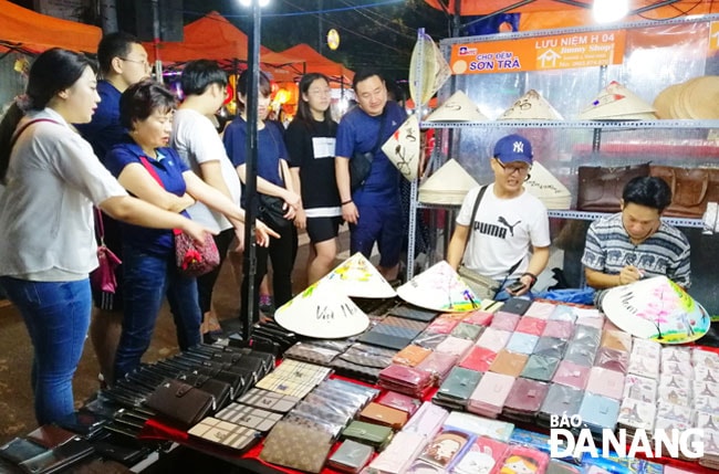 Cần có những sản phẩm chuyên biệt, gắn với đặc trưng của địa phương để thu hút khách hơn nữa. Trong ảnh: Du khách Hàn Quốc đang mua sắm tại gian hàng quà tặng vẽ tay Jimmy shop tại chợ đêm Sơn Trà. Ảnh: Thu Hà