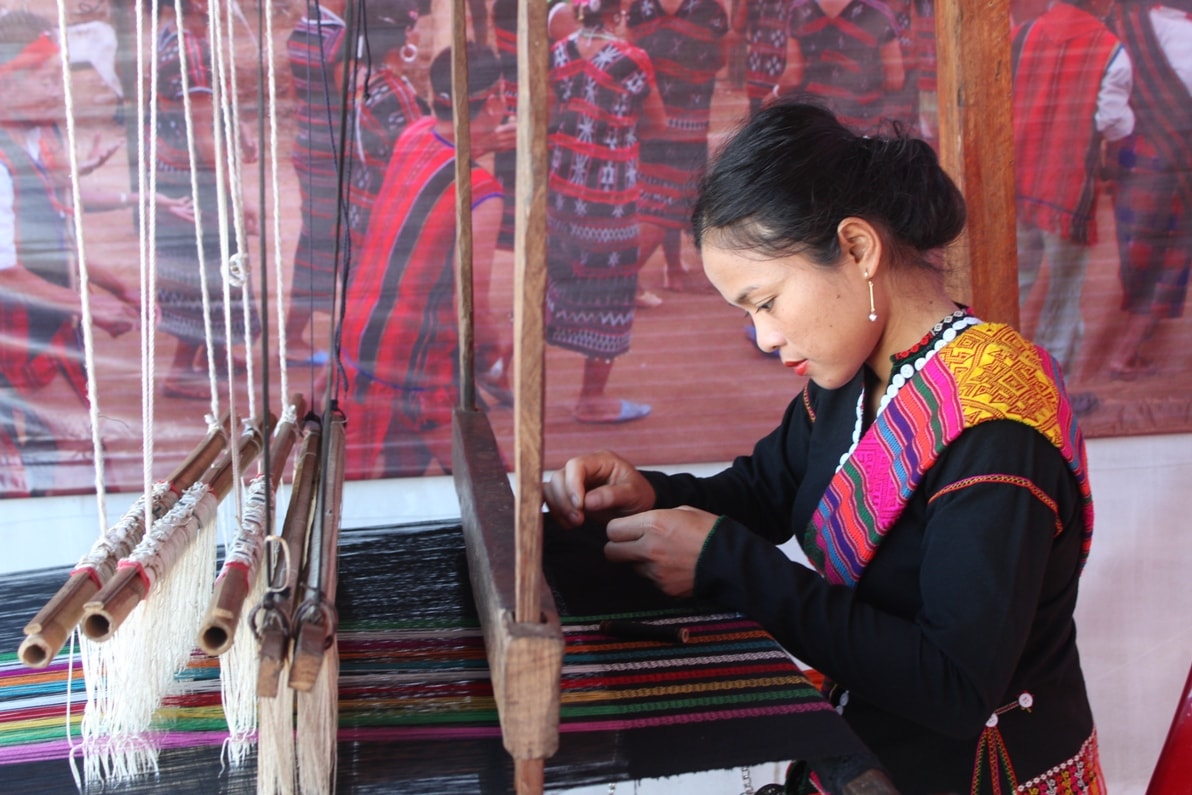 A woman is weaving brocade.