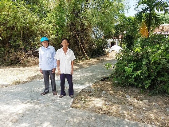 Ông Trương Công Hiếu (trái) và con trai bà Chức đứng trên lối đi bằng bê tông mà hàng xóm xây dựng trái phép xuyên qua thửa đất của gia đình. Ảnh: H.S