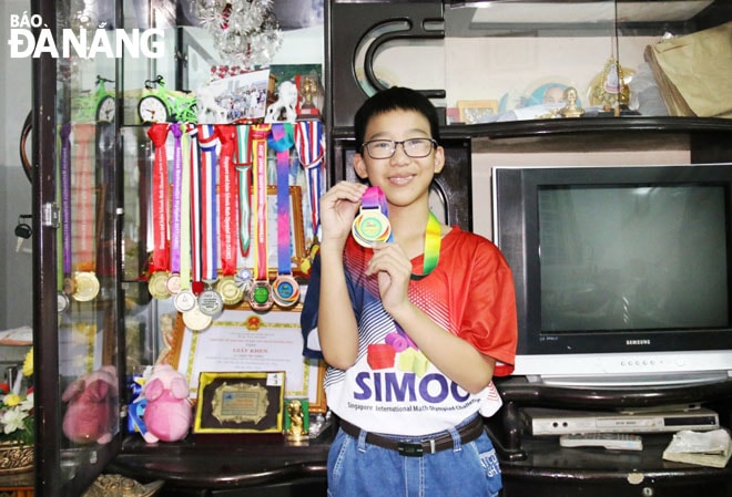 Đặng Văn Thành bên những tấm huy chương Toán học em giành được trong những năm qua. Ảnh: T.T