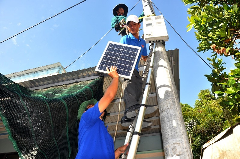 Lực lượng thanh niên tình nguyện hỗ trợ đơn vị thi công lắp đặt đèn năng lượng mặt trời cho nhân dân Cù Lao Chàm. Ảnh: V.ANH