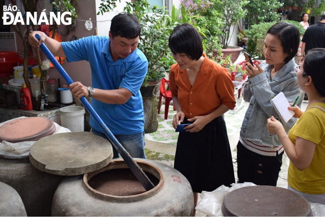 Người dân làng nghề nước mắm Nam Ô giới thiệu về phương pháp làm mắm theo công thức gia truyền “ 3 cá 1 muối”. Ảnh: KHÁNH HÒA