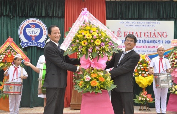 Thay mặt lãnh đạo tỉnh, Trưởng ban Nội chính Tỉnh ủy Nguyễn Ngọc Truyền (bìa trái) tặng hoa chúc mừng Trường THCS Nguyễn Du. Ảnh: N.Đ