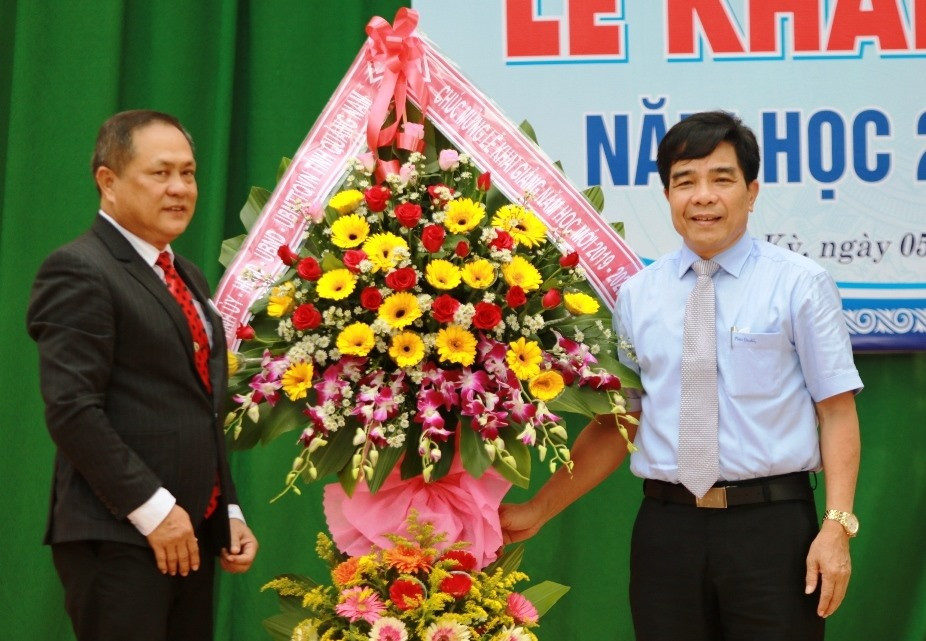 Phó Bí thư Thường trực Tỉnh ủy Lê Văn Dũng (bìa phải) tặng lẵng hoa chúc mừng thầy và trò Trường THPT Trần Cao Vân. Ảnh: T.C
