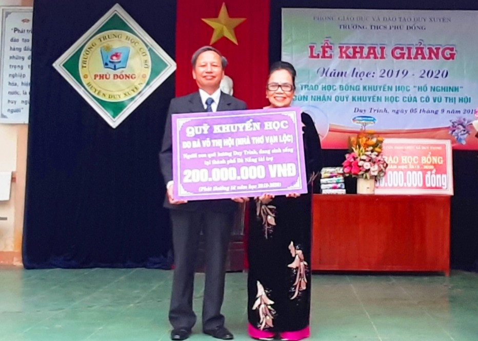 Bà Võ Thị Hội trao 200 triệu đồng cho đại diện Trường THCS Phù Đổng. Ảnh: HOÀI NHI