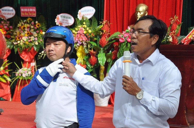 Đại diện Ban An toàn giao thông tỉnh cùng nhân viên Công ty Honda Việt Nam hướng dẫn cách đội MBH cho học sinh. Ảnh: V.ANH