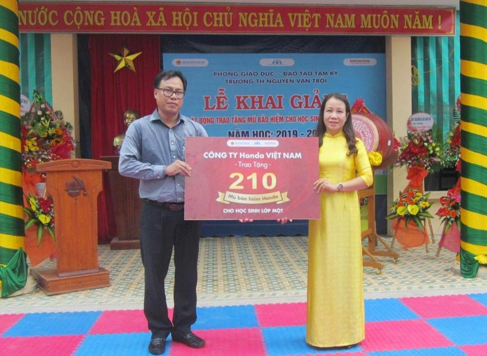 Lãnh đạo Trường Tiểu học Nguyễn Văn Trỗi (phải) nhận bảng tượng trưng trao tặng 210 MBH từ Công ty Honda Quốc Tiến 2 Tam Kỳ. Ảnh: C.N