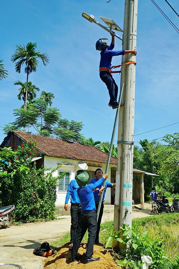 Đoàn viên thanh niên huyện Tiên Phước tham gia lắp đặt điện chiếu sáng tại thôn Thanh Bôi (xã Tiên Châu). Ảnh: NGUYỄN ĐIỆN NGỌC