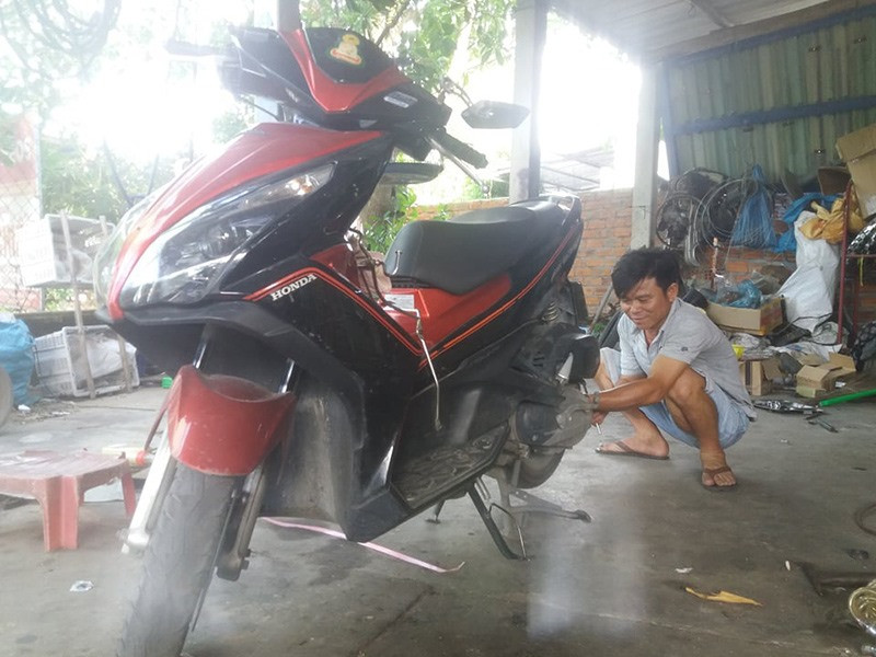 Anh Trần Văn Chiến với công việc sửa xe máy.