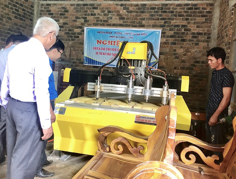 Việc áp dụng máy CNC trong sản xuất góp phần tăng năng suất và chất lượng sản phẩm. Trong ảnh: Anh Đại (áo đen bên phải) đang giới thiệu về máy CNC. Ảnh: SƯƠNG TÂN