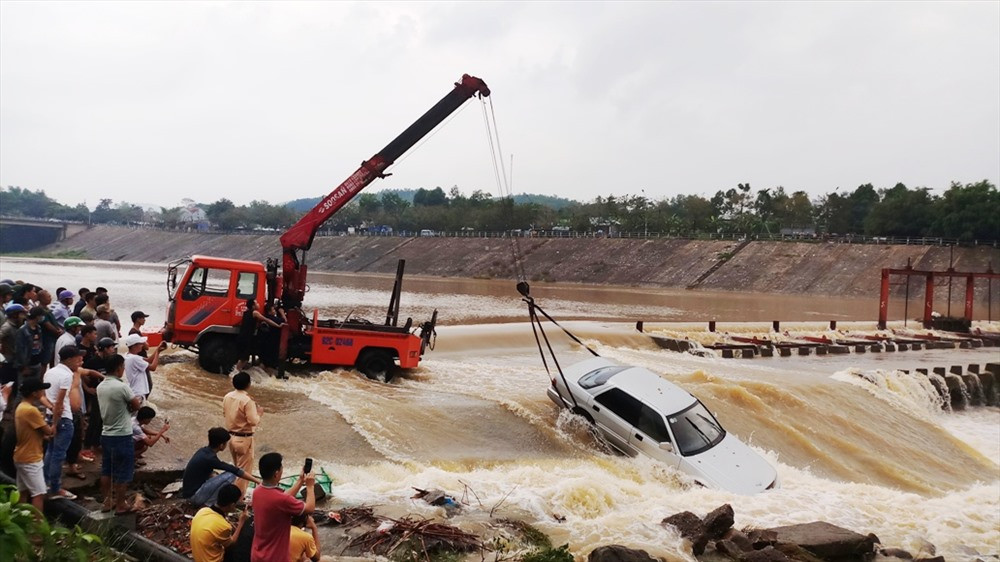 Lực lượng cứu hộ cẩu chiếc ô tô gặp nạn khỏi dòng nước. Ảnh: N.HƯNG