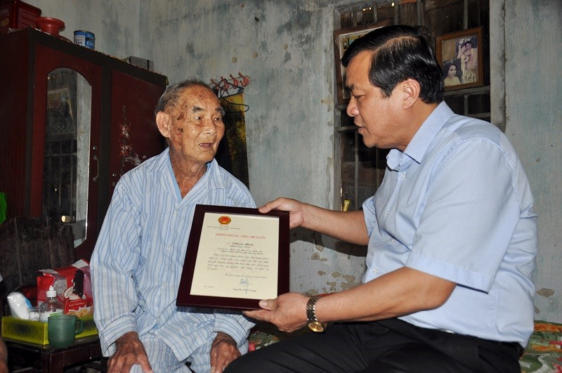 Bí thư Tỉnh ủy Phan Việt Cường trao “Thiệp mừng thọ tròn 100 tuổi” cho cụ Phạm Minh. Ảnh: VINH ANH