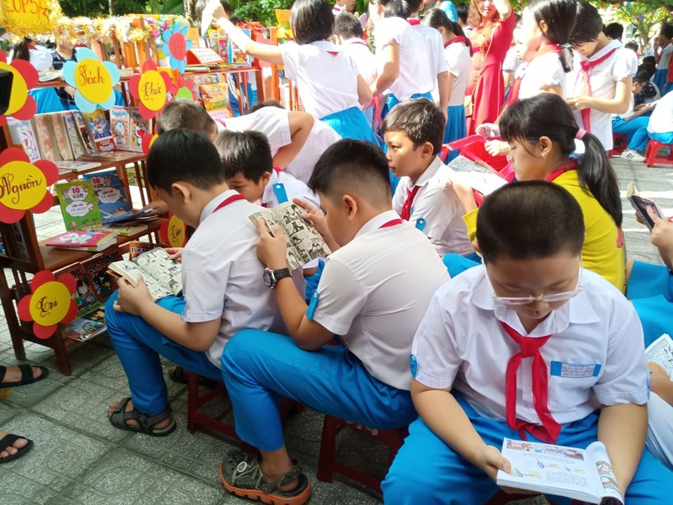 Học sinh đọc sách ở sân trường trong ngày khánh thành thư viện thân thiện. Ảnh: C.N